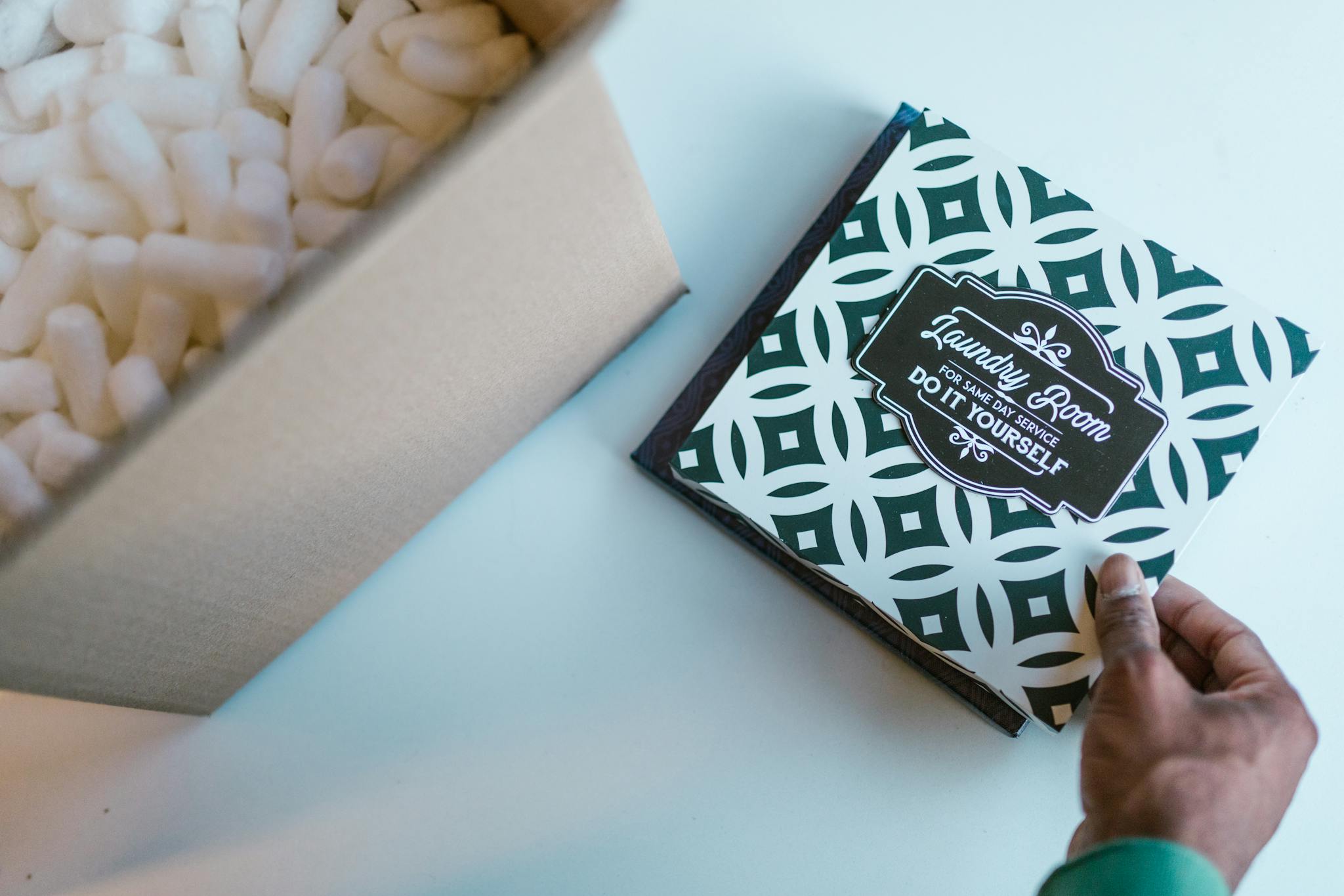 Close-up of hand holding a box with packing peanuts and a branded card design.